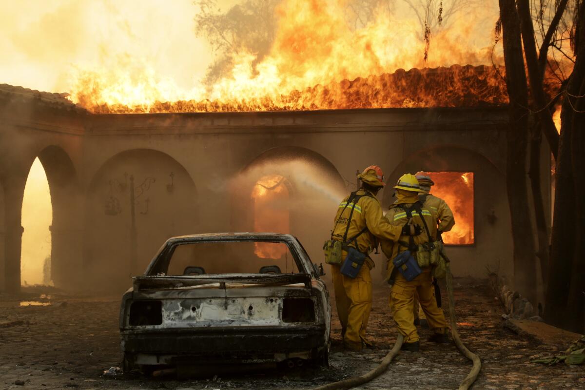 Firefighters try to protect the main house of the Singer Mansion on Kregmont Drive in Glendora on Jan. 16. The mansion was one of the structures damaged by the Colby fire.