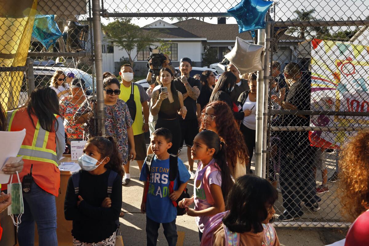 Parents watch as their students enter school yard gates.