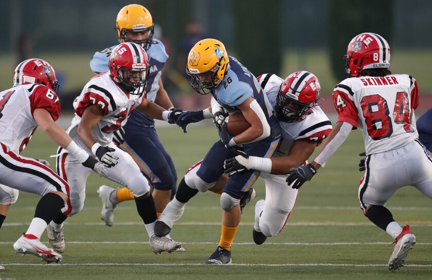 Marina's Dominic Harvey (26) is met by a host of Elsinore tacklers.