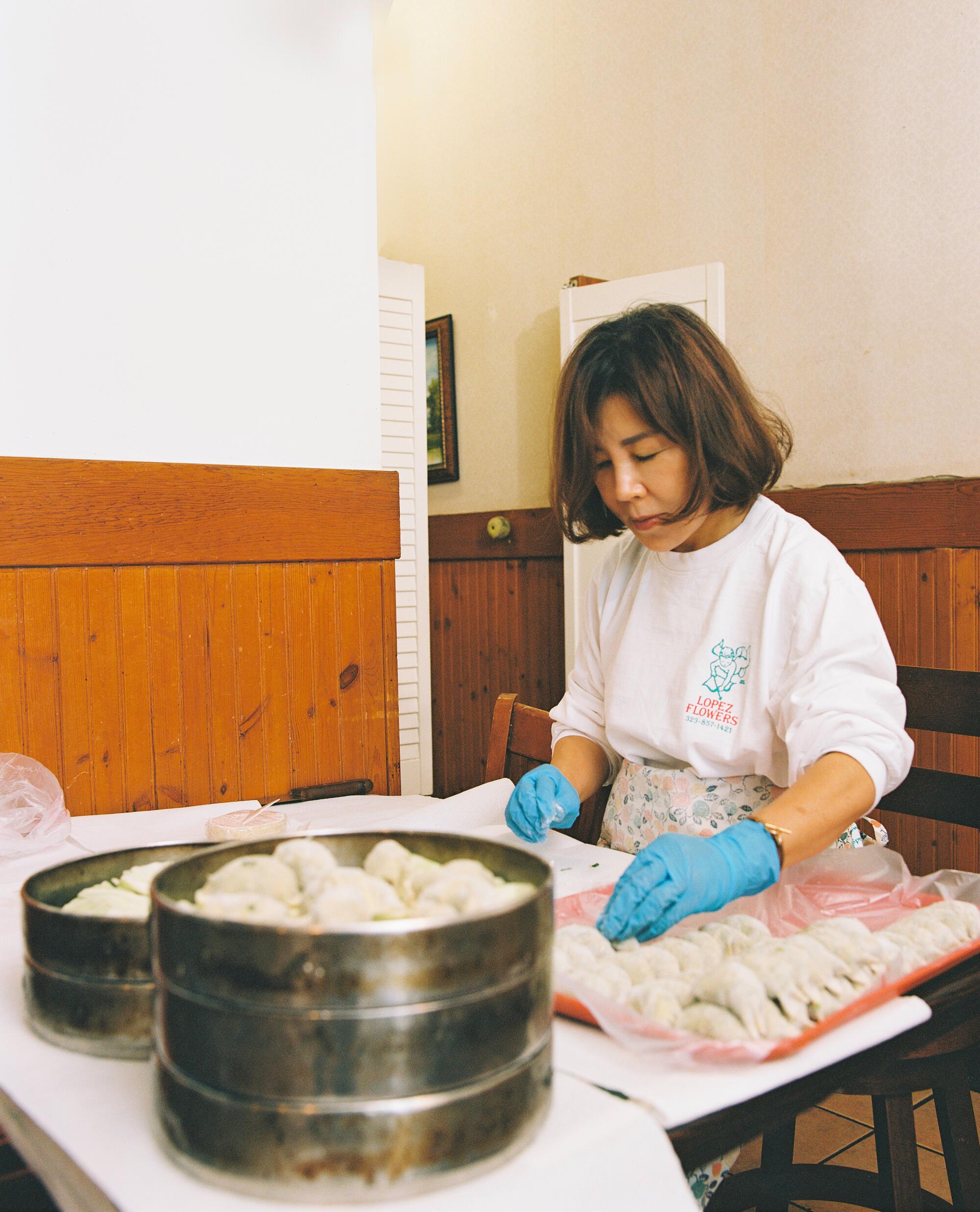 A woman prepares dumplings in a restaurant.