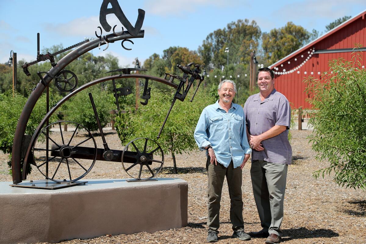 Jon Seeman, left, and City Manager Dave Doyle stand beside Seeman's "Onward" sculpture.