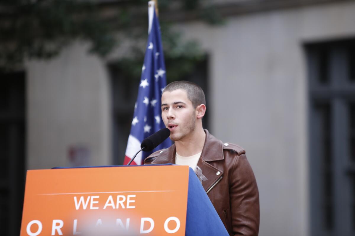 Nick Jonas speaks at a lectern with the words "WE ARE ORLANDO" on it.