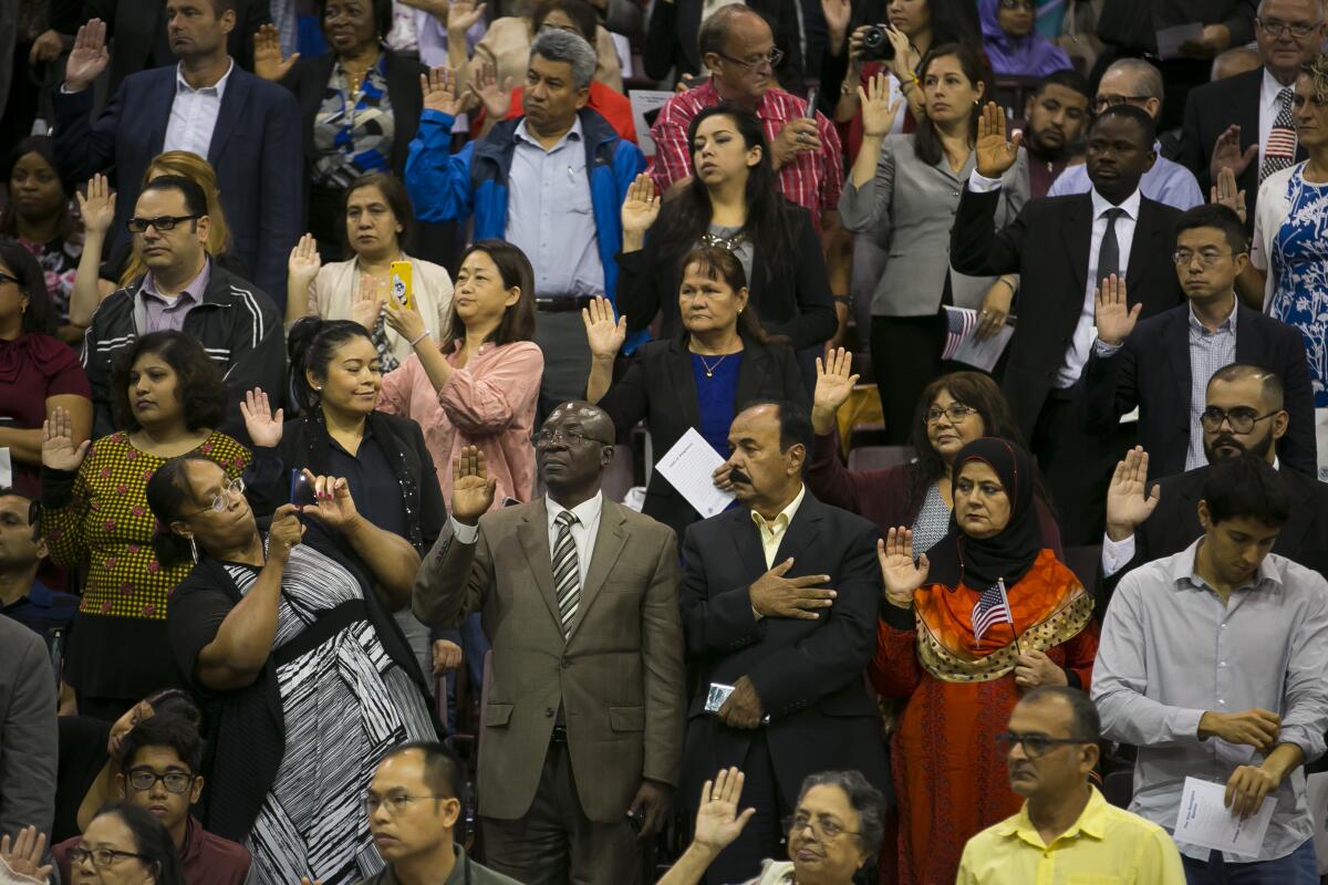 Immigrants raise their hands to take the oath of allegiance during a recent naturalization ceremony in Houston.