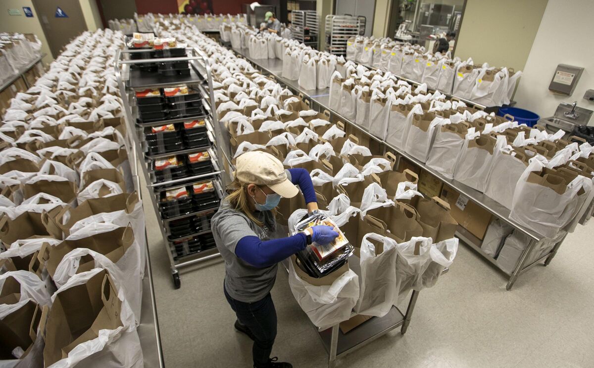 Volunteer Lisa Hatfield works assembling some of the 607 bags of food that will be delivered to clients at the Mama's Kitchen commissary on Home Avenue in Fairmont Park on Friday, April 10. Requests for food have risen 40 percent since the coronavirus pandemic began. The organization serves the dietary needs of people with HIV, cancer, congestive heart failure and type 2 diabetes.