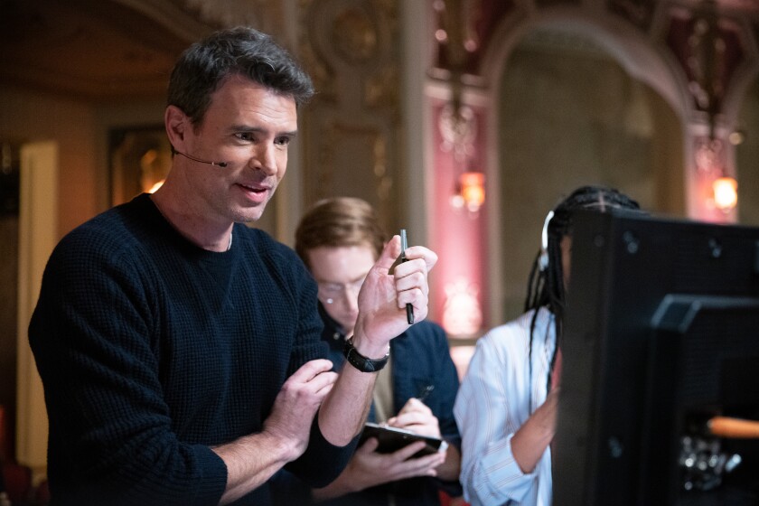 A TV producer standing at a monitor wearing a headset
