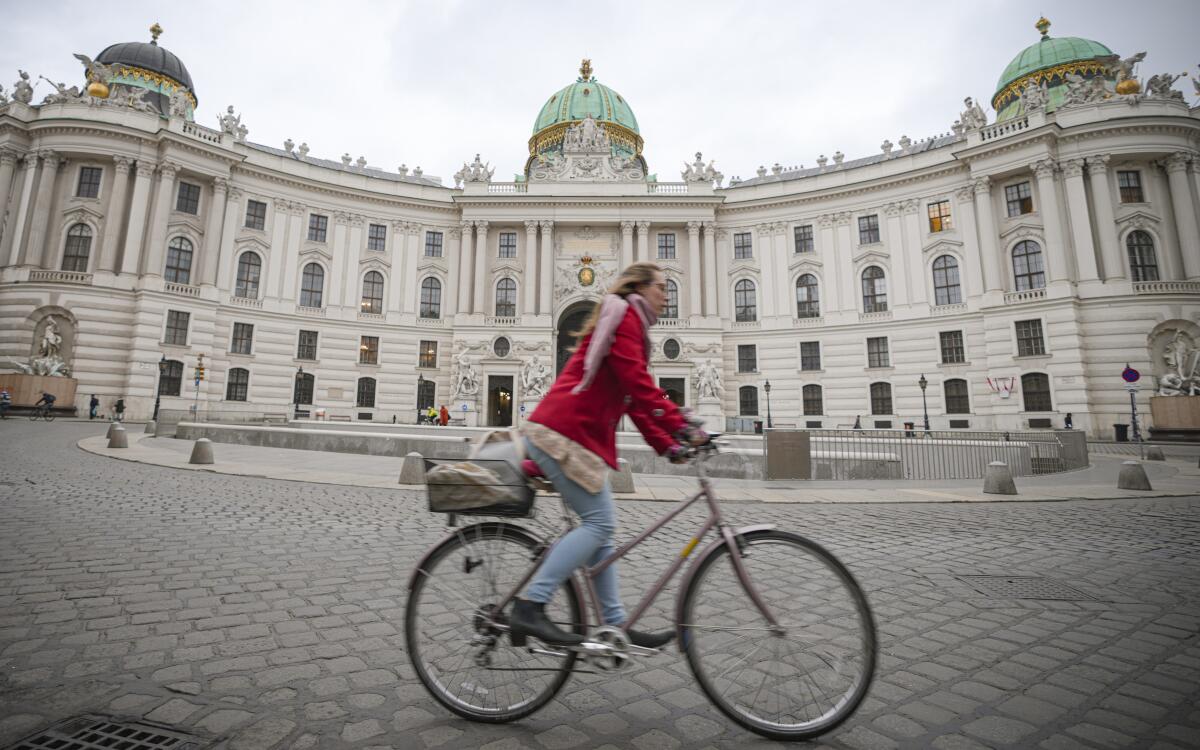 A woman rides a bicycle along an empty street in Vienna