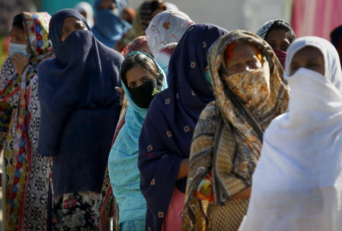 Christian women wait their turn to receive free sacks of wheat flour and other food supplies provided by a charity group Act of Kindness Pakistan in Rawalpindi, Pakistan, Saturday, May 16, 2020. Pakistan relaxed the weeks-long lockdown that was enforced to curb the spread of the coronavirus, as health officials fear an increase of COVID-19 cases. (AP Photo/Anjum Naveed)