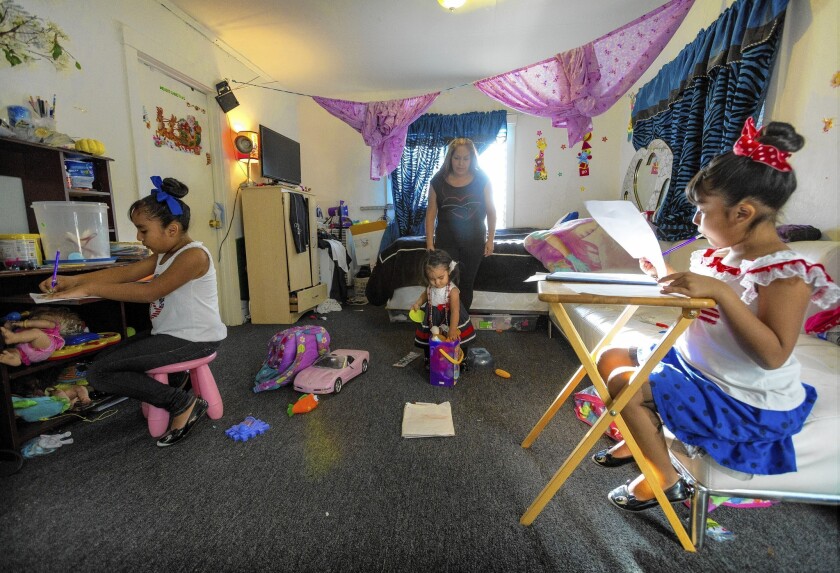 Sisters Ashley Orosco, left, and Lindsay study as their mom, Melina Vasquez, cares for Alexa in a rent-controlled Echo Park complex where all residents are being evicted.