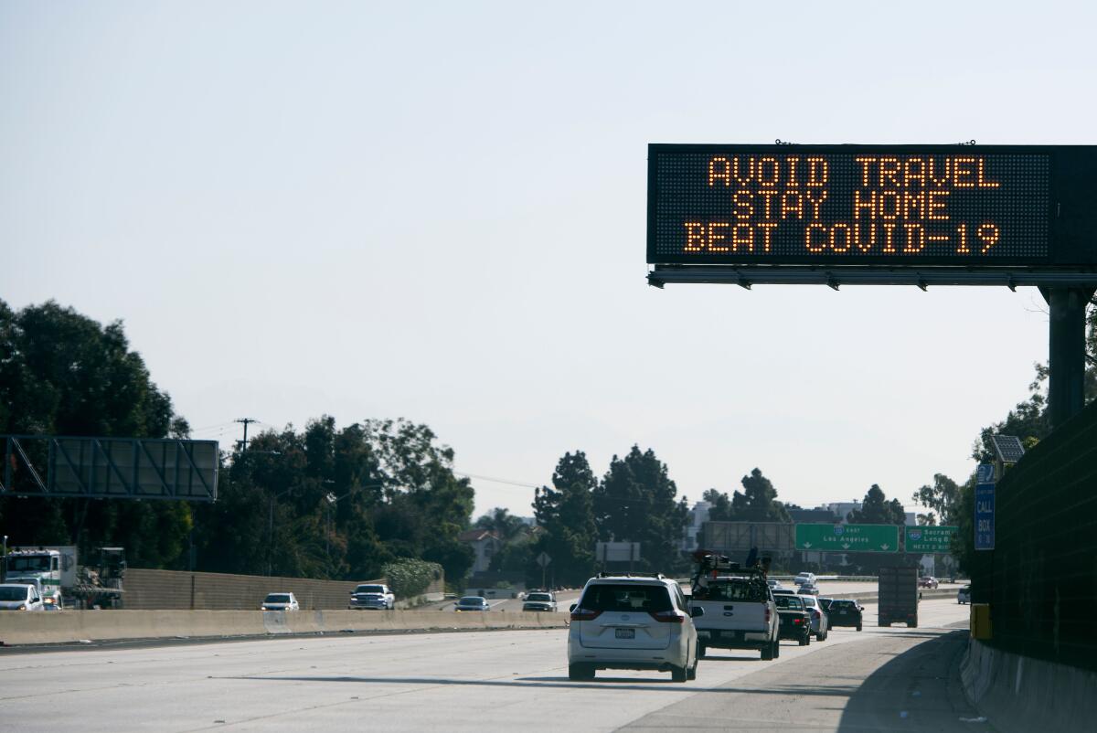 A sign asking for drivers to "avoid travel and stay home" due to the spread of coronavirus (COVID-19) is displayed over the I10 freeway on April 14, 2020, in Santa Monica, California.