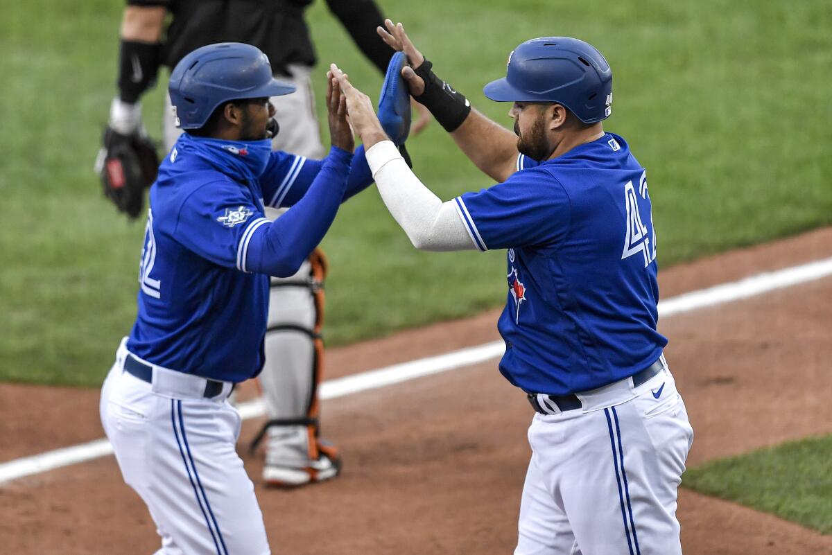 Rowdy Tellez (derecha) y Teoscar Hernández, de los Azulejos de Toronto, festejan tras anotar 