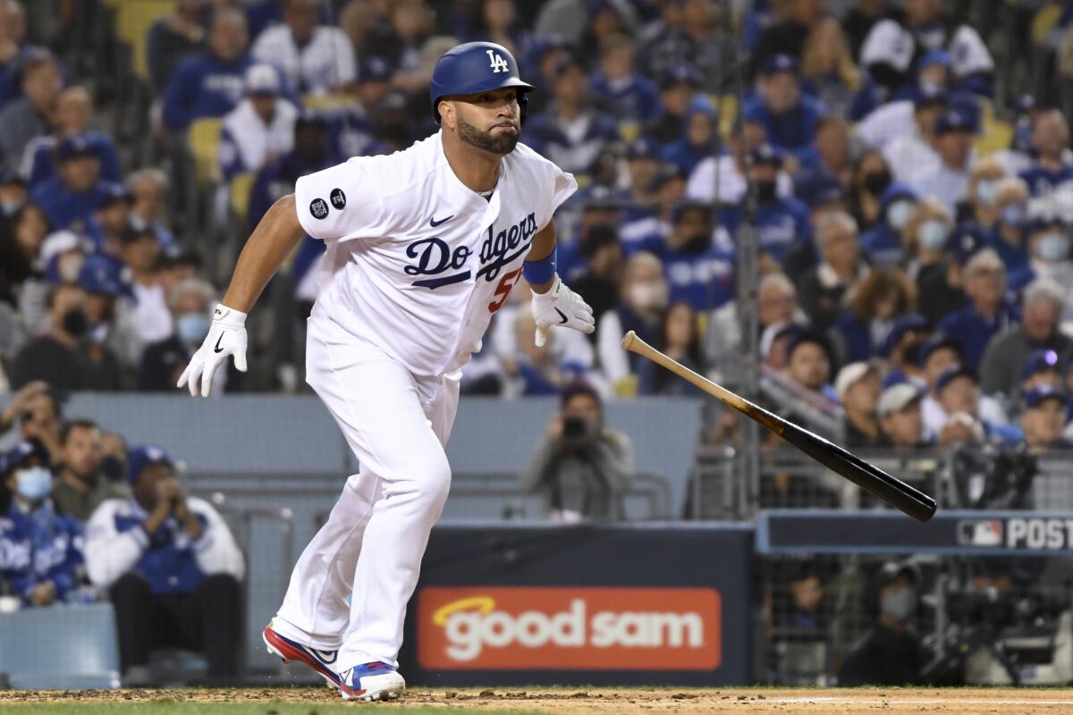 Dodgers first baseman Albert Pujols tosses his bat after hitting a single.