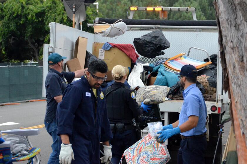 Workers loaded a truck with encampment belongings strewn along Avocado Avenue on Thursday.