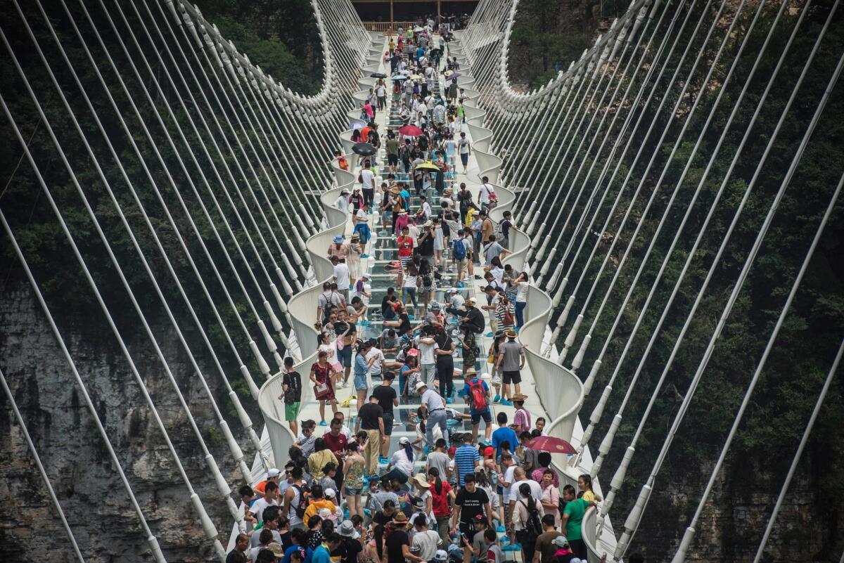 Visitors cross the world's highest and longest glass-bottomed bridge above a valley in Zhangjiajie in China's Hunan province the day after its Aug. 20 opening.