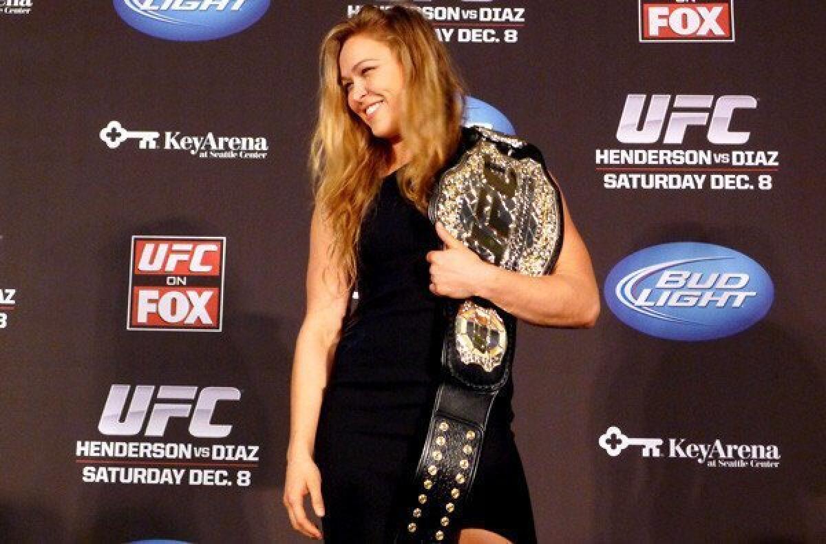 FILE - In this Dec. 6, 2012, file photo, mixed martial arts fighter Ronda Rousey shows off her UFC bantamweight championship belt presented to her by UFC president Dana White during a news conference in Seattle. With her Olympic pedigree and merciless mixed martial arts success, Rousey finally has a showcase worthy of her talent. Rousey and Liz Carmouche are about to make history in the main event at UFC 157 in Anaheim on Saturday, in the first women's bout in the promotion's history. (AP Photo/The Canadian Press, Neil Davidson, File) ** Usable by LA and DC Only **