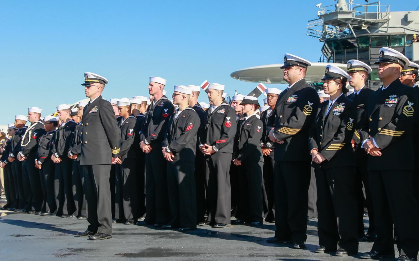 Sailors from the ship called, USS Pearl Harbor stand at attention.