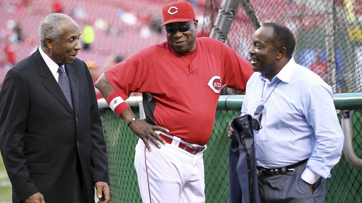 Hall of Famers Frank Robinson, left, and Joe Morgan, right, chat with Dusty Baker — then manager of the Cincinnati Reds — during a batting practice in 2010.