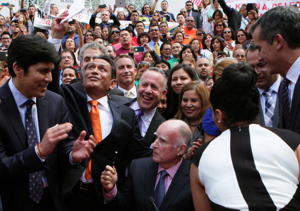 State Sen. Kevin de Leon, from left, Los Angeles City Councilman Gil Cedillo, Senate President Pro Tem Darrell Steinberg and Mayor Eric Garcetti are in a jubilant mood after Gov. Jerry Brown signed a bill signing to allow immigrants lacking legal immigration status to get California driver's licenses.