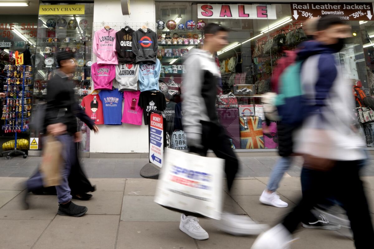 Londra'nın Oxford Caddesi'nde bir hediyelik eşya dükkanının önünden geçen alışverişçiler