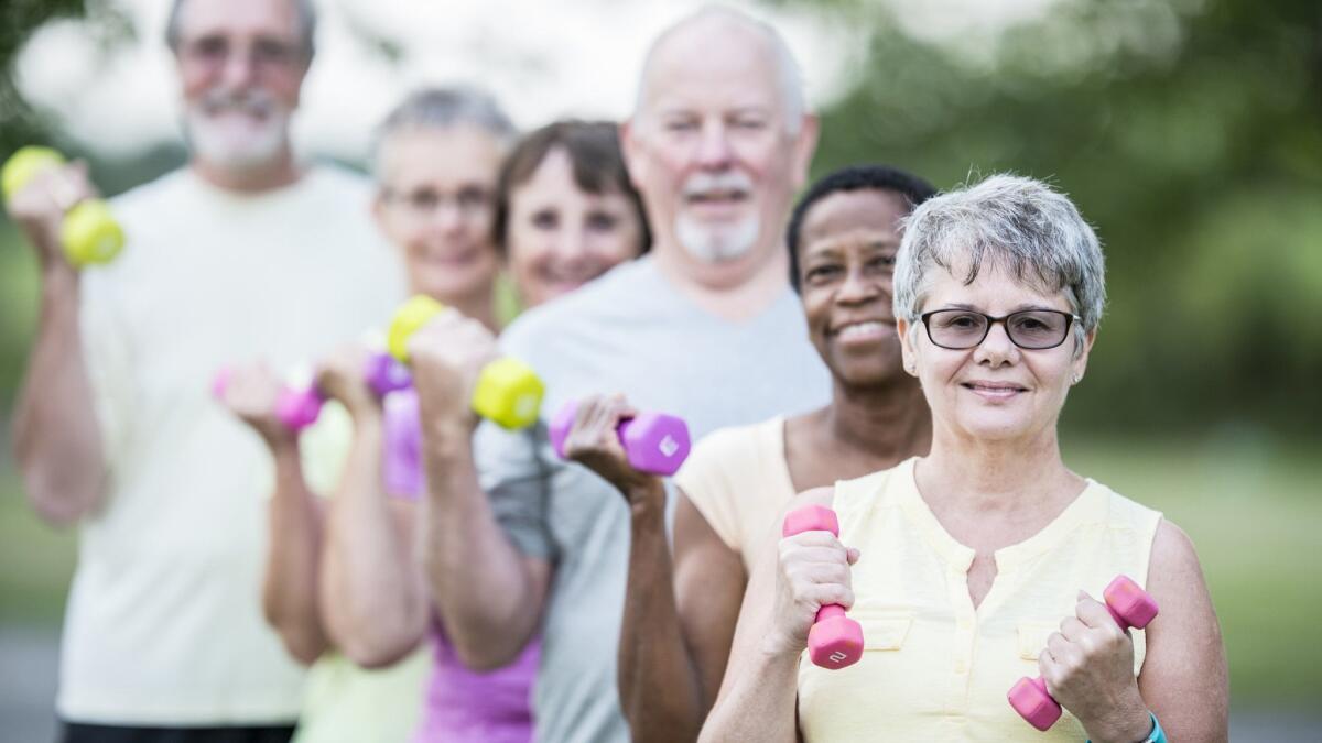 A group of seniors lifting weights in a park. The World Health Organization says exercise and a healthy diet are best for reducing dementia risk.