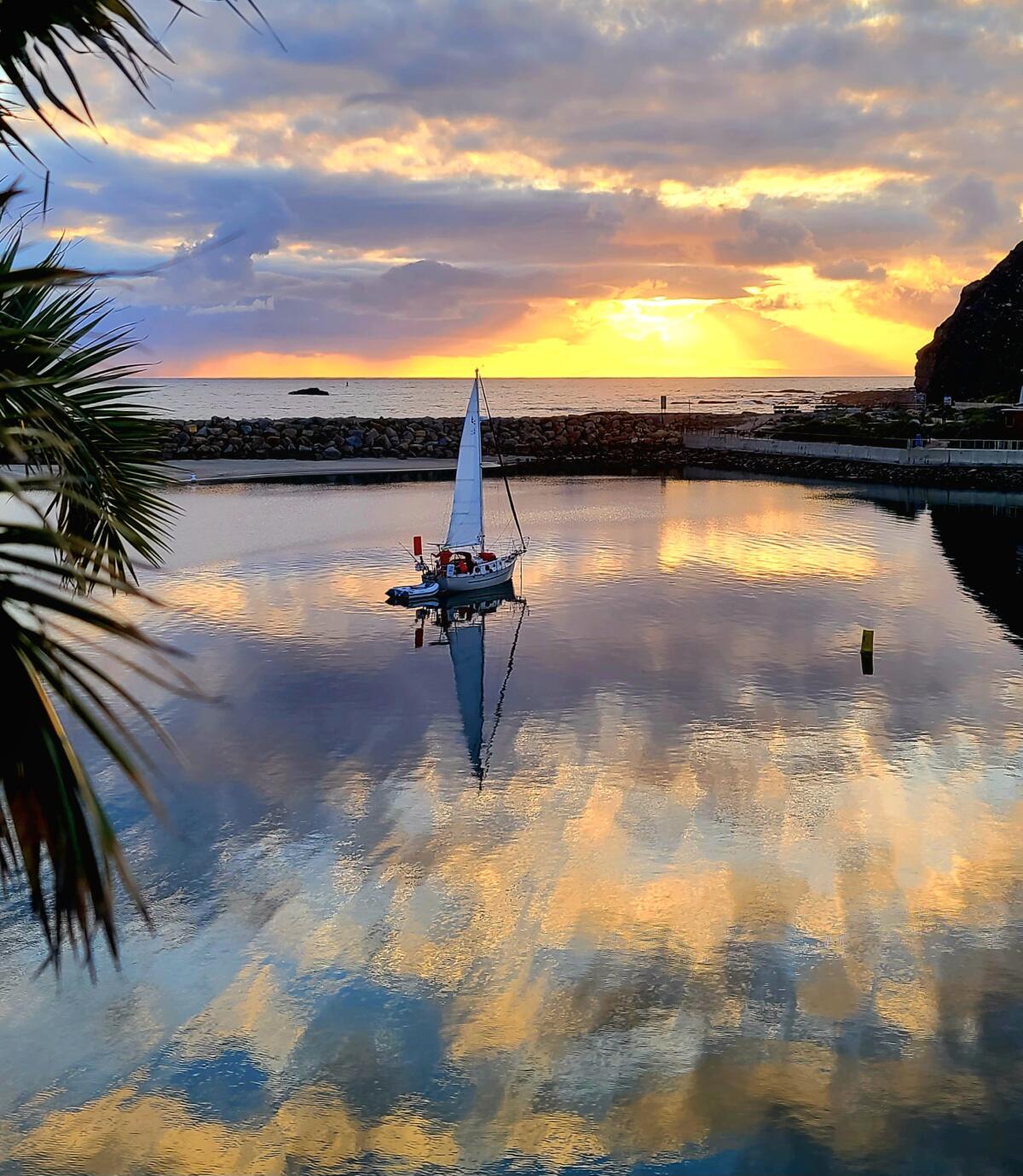 A small boat is seen in a lagoon that reflects the sunset.