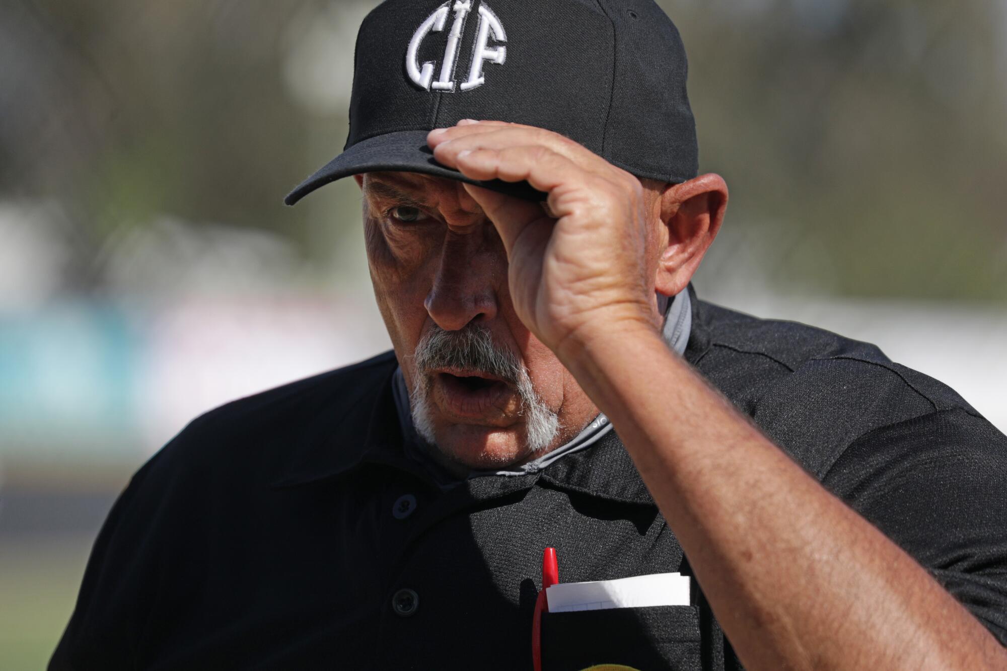 Plate umpire Jeff Sill adjusts his cap during a game between Thousand Oaks and Newbury Park.