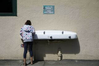 In this Sept. 16, 2015 photo, a student drinks from a water fountain below a sign signaling the water as safe to drink at Westport Elementary School in Ceres, Calif. The school, which draws on its own wells for its drinking fountains, sinks and cafeteria, is one of about 10 water systems in the farm region to install a uranium removal facility on site. (AP Photo/John Locher)