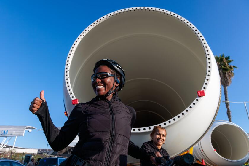 LOS ANGELES, CA - OCTOBER 11: A resident gets her photo taken one of two large Solid Rocket Motors on the way to California Science Center to join display of the space shuttle Endeavour, traveling on Figueroa Street on Wednesday, Oct. 11, 2023 in Los Angeles, CA. (Irfan Khan / Los Angeles Times)