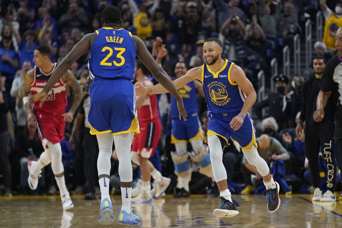 Golden State Warriors guard Stephen Curry (30) is congratulated by forward Draymond Green (23) after shooting a 3-point basket during the first half of an NBA basketball game against the Washington Wizards in San Francisco, Monday, March 14, 2022. (AP Photo/Jeff Chiu)