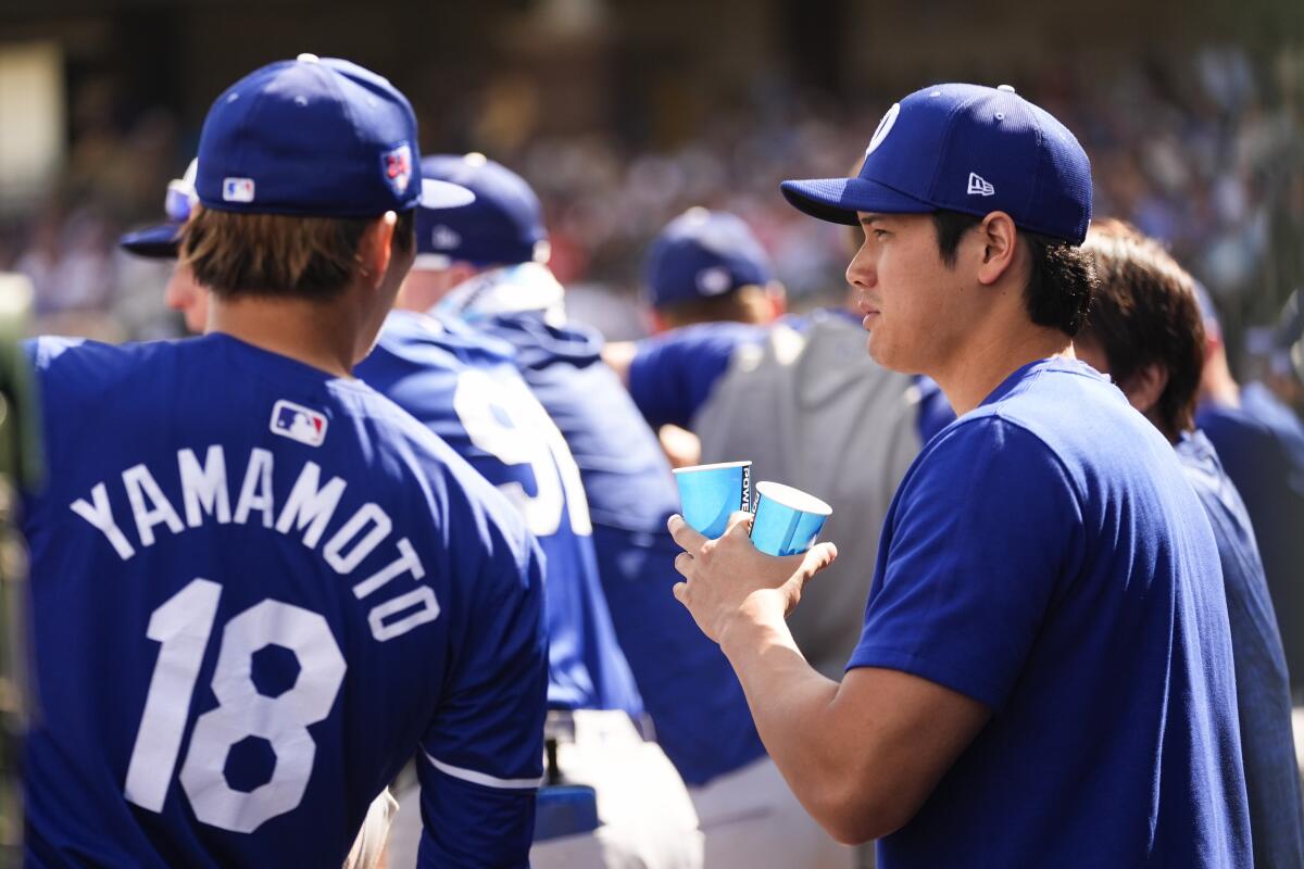 Yoshinobu Yamamoto, left, talks with Dodgers teammate Shohei Ohtani in the dugout after pitching against the Rangers.