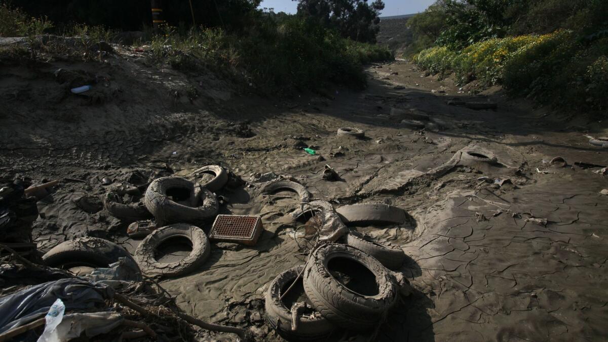 Along Monument Road in the area just north of the U.S. - Mexico border, the northward flow of storm runoff brings piles of tires, plastic bottles, sediment and polluted wastewater into the Tijuana River Estuary. | Mandatory photo credit: Peggy Peattie / San Diego Union-Tribune