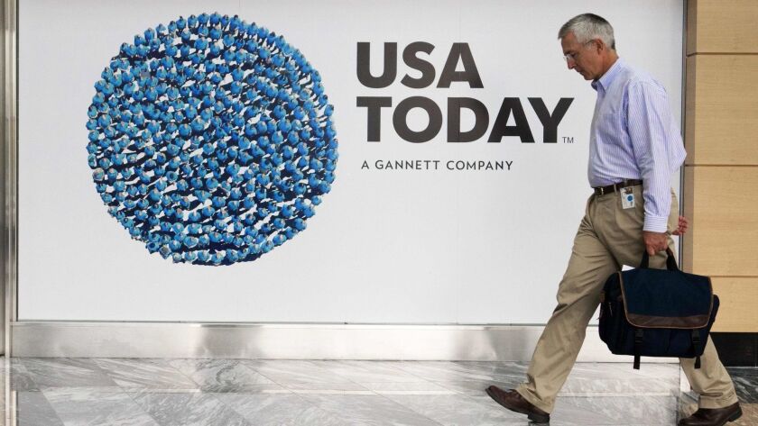 A Gannett employee walks past a promotional display for its flagship USA Today newspaper in the company's McLean, Va., headquarters.