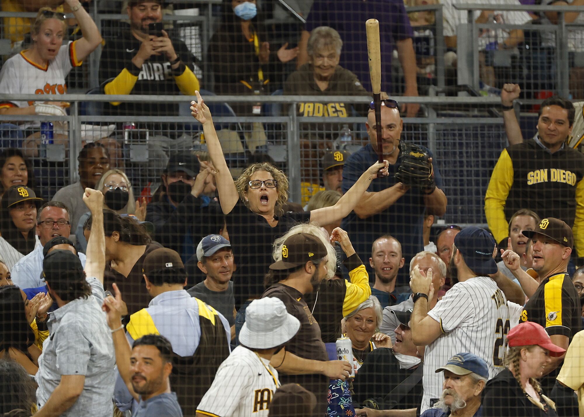 A fan holds up a bat that flew out of the hands of Rockies' Elehuris Montero into the 