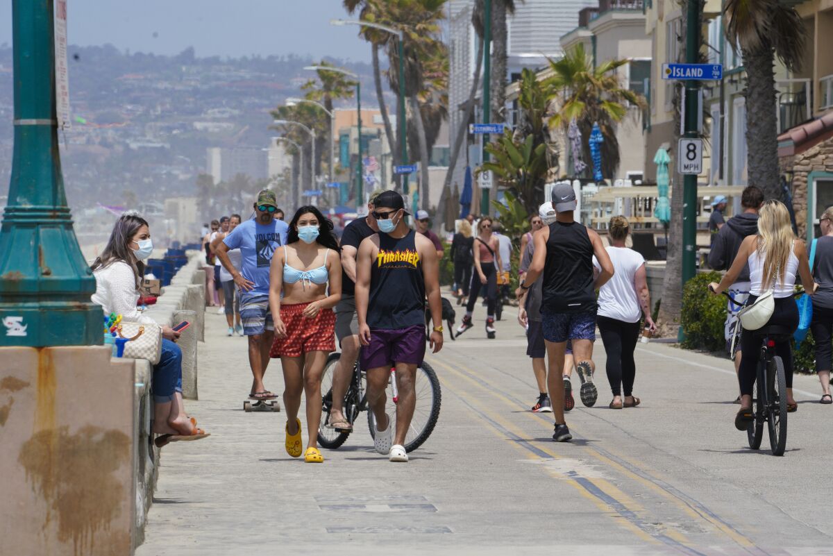 Warm weather brought the largely masked public out to the boardwalk in Mission Beach in May as the first Delta cases arrived.
