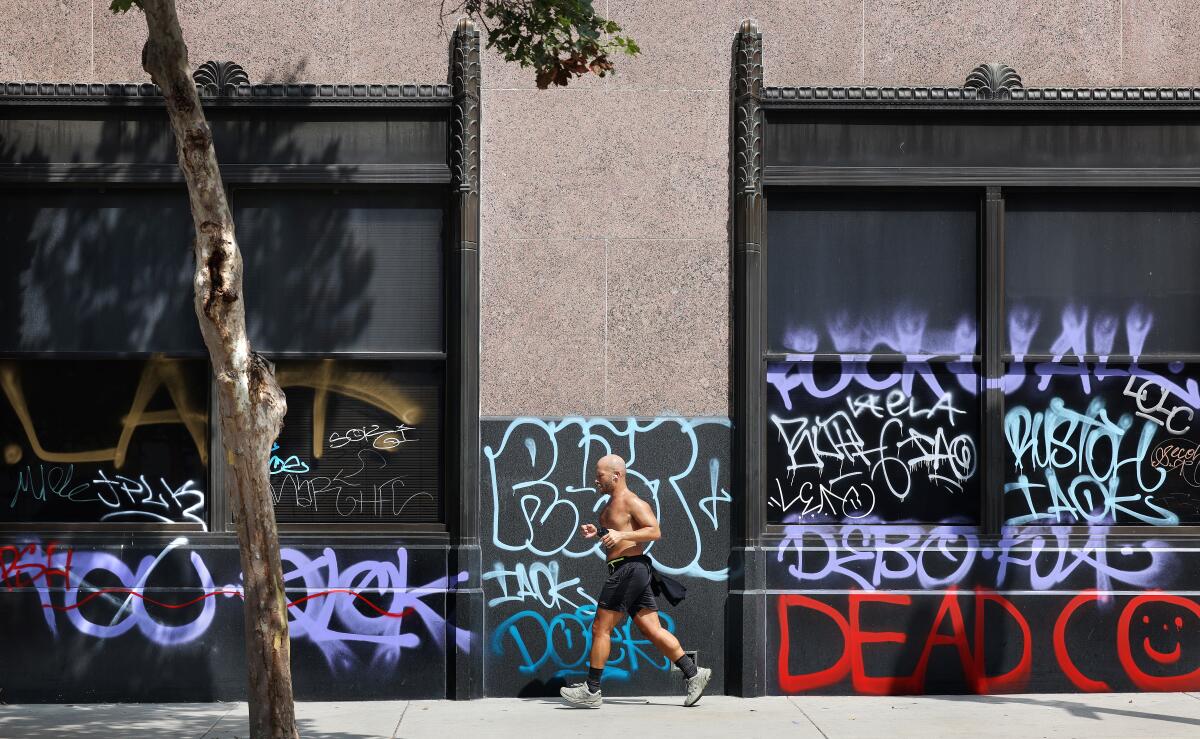 A runner on Wednesday passes by graffiti scrawled on the building that for many years housed the Los Angeles Times.