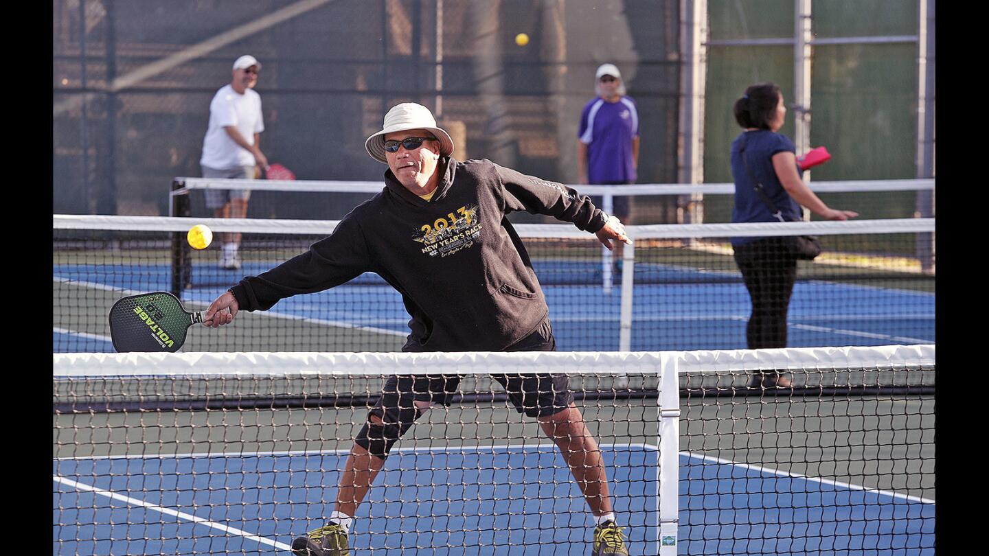Roland Sunga, of Burbank, reaches to hit the ball back into play on opening day of full-time pickleball courts at Larry Maxam Memorial Park in Burbank on Monday, April 9, 2018. A group of 60 enthusiastic pickleball players put together $20,000 to work with City of Burbank Parks and Recreation to officially redesign the court for permanent pickleball usage.