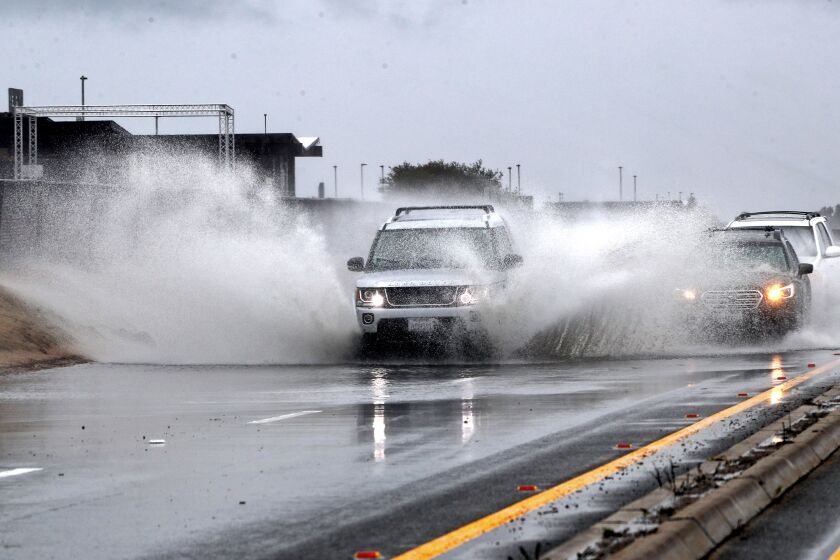 Vehicles pass through flooded areas on Pacific Coast Highway between Warner and Seapoint St., on a rainy morning, in Huntington Beach on March 3, 2021.