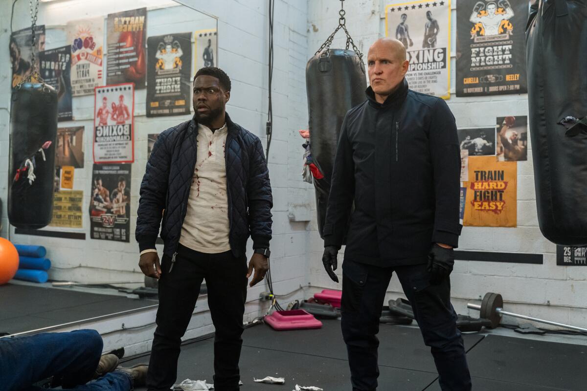 Two jacketed men, one with blood on his shirt, in a boxing gym