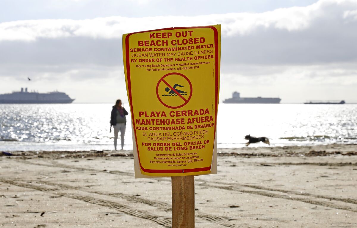 A sign on a beach says "Keep Out, Beach Closed, Sewage Contaminated Water."