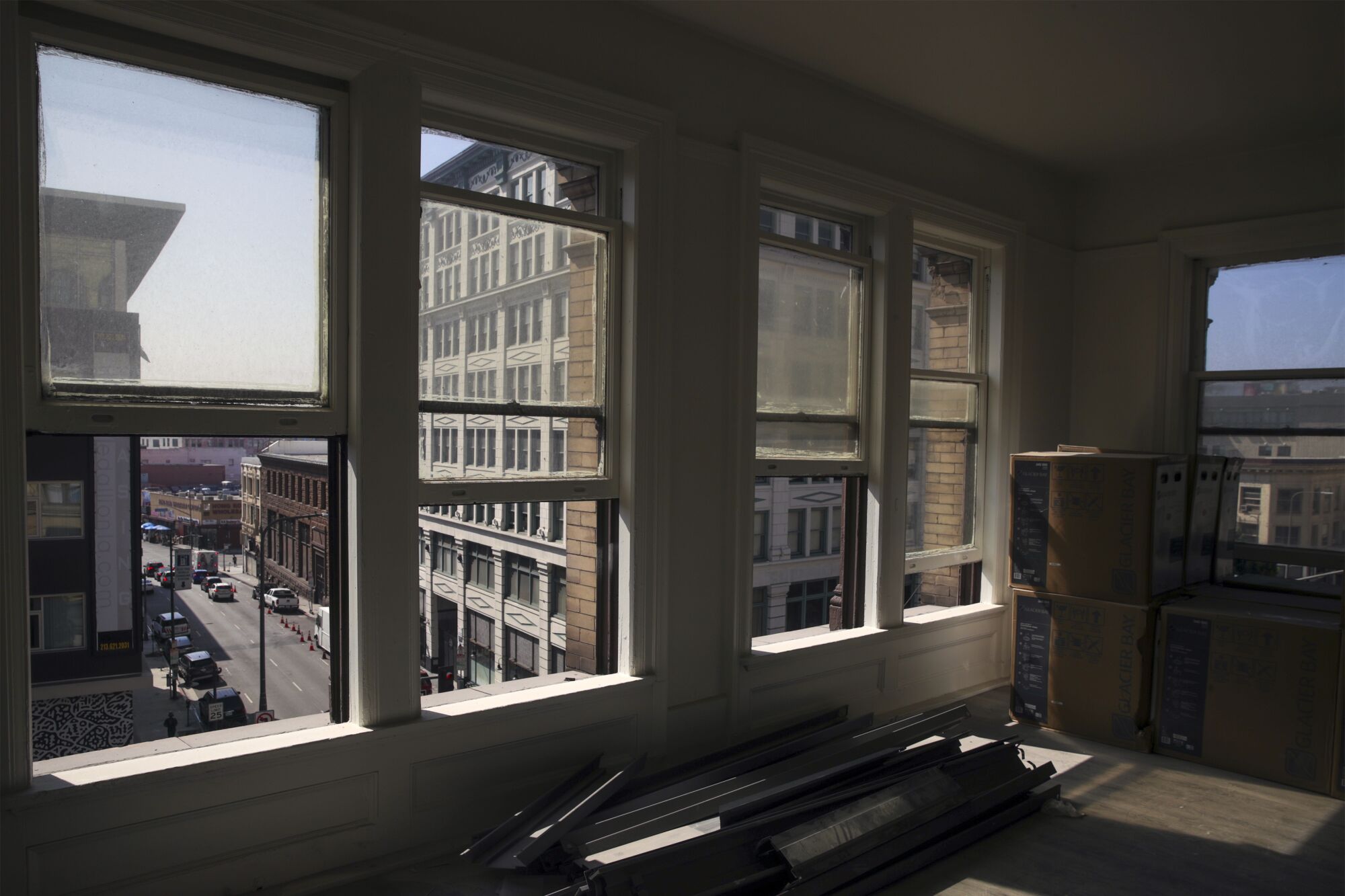 A view from inside and across a room under construction, with a sunlit street and buildings visible outside.