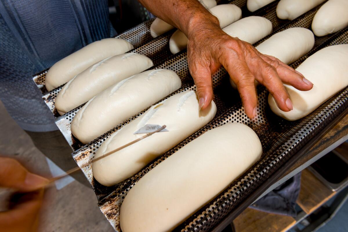 Baker Van No Nguyen slices slits on banh mi loaves using a Bic razor blade attached to a bamboo stick.