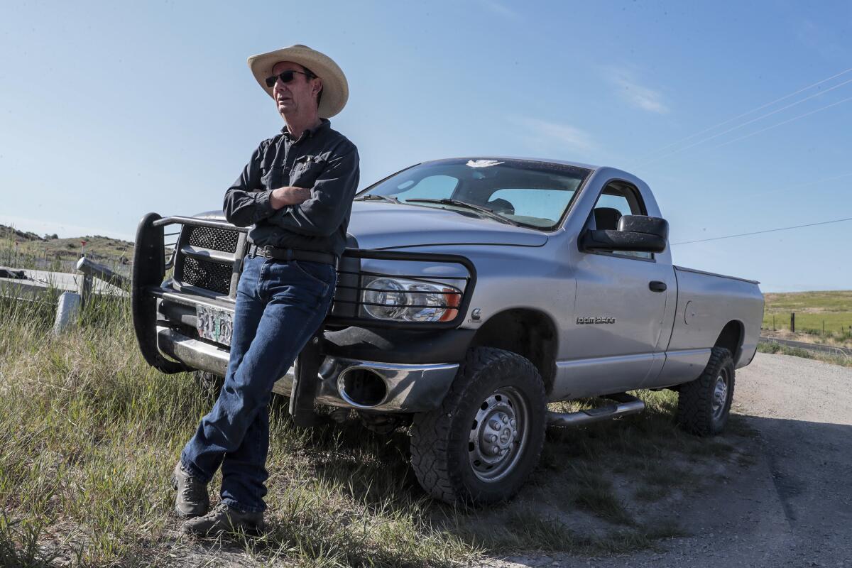 A man in a cowboy hat leans against a truck