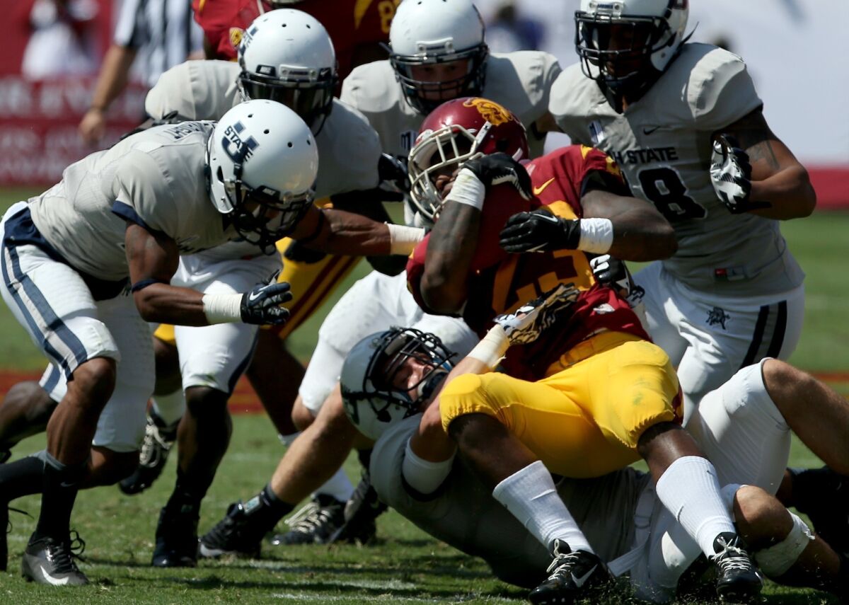 USC trailback Tre Madden is met by a swarm of Utah State defenders in the first quarter Saturday. The Aggies held Madden to 93 yards in 24 carries Saturday, the first time the Trojans running back didn't gain at least 100 yards this season.