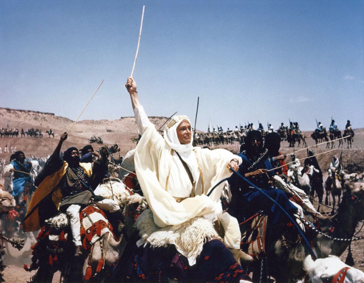 An Englishman in Arab dress rides a camel 