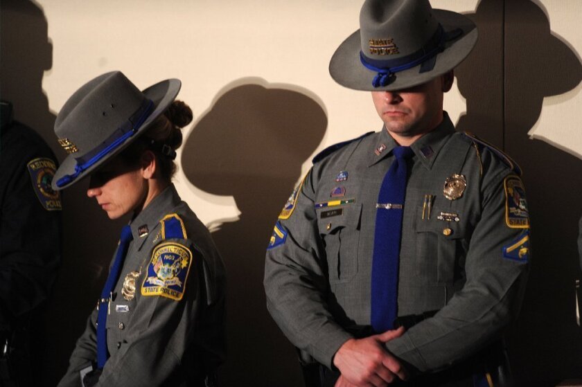 Connecticut State Troopers bow their heads during an interfaith vigil for the shooting victims from Sandy Hook Elementary School.