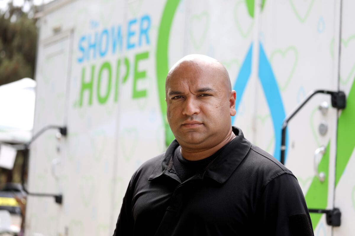 A man stands in front of a Shower of Hope unit