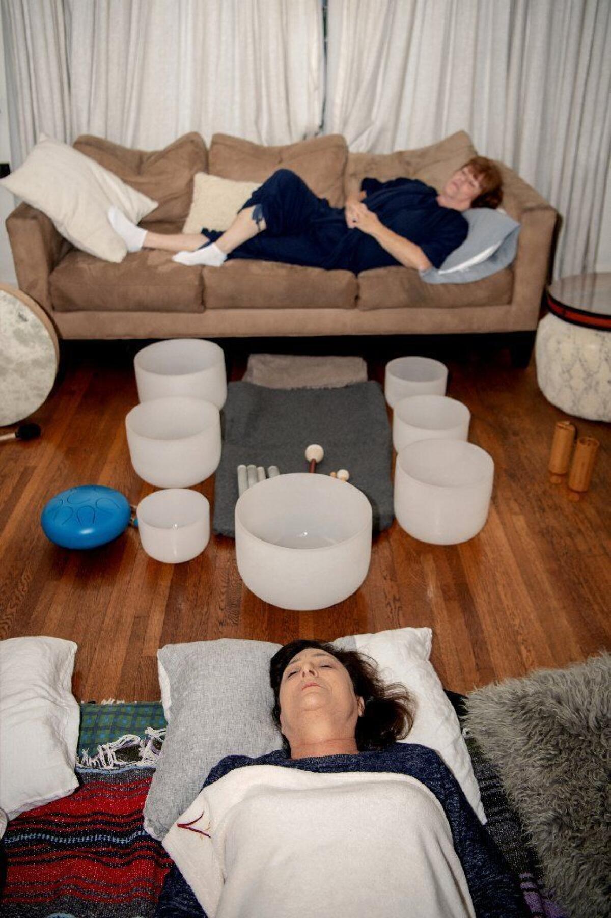 Eileen Klauber (top) and Linda Fenton get comfortable as the two prepare for the sound bath at Heim's home.