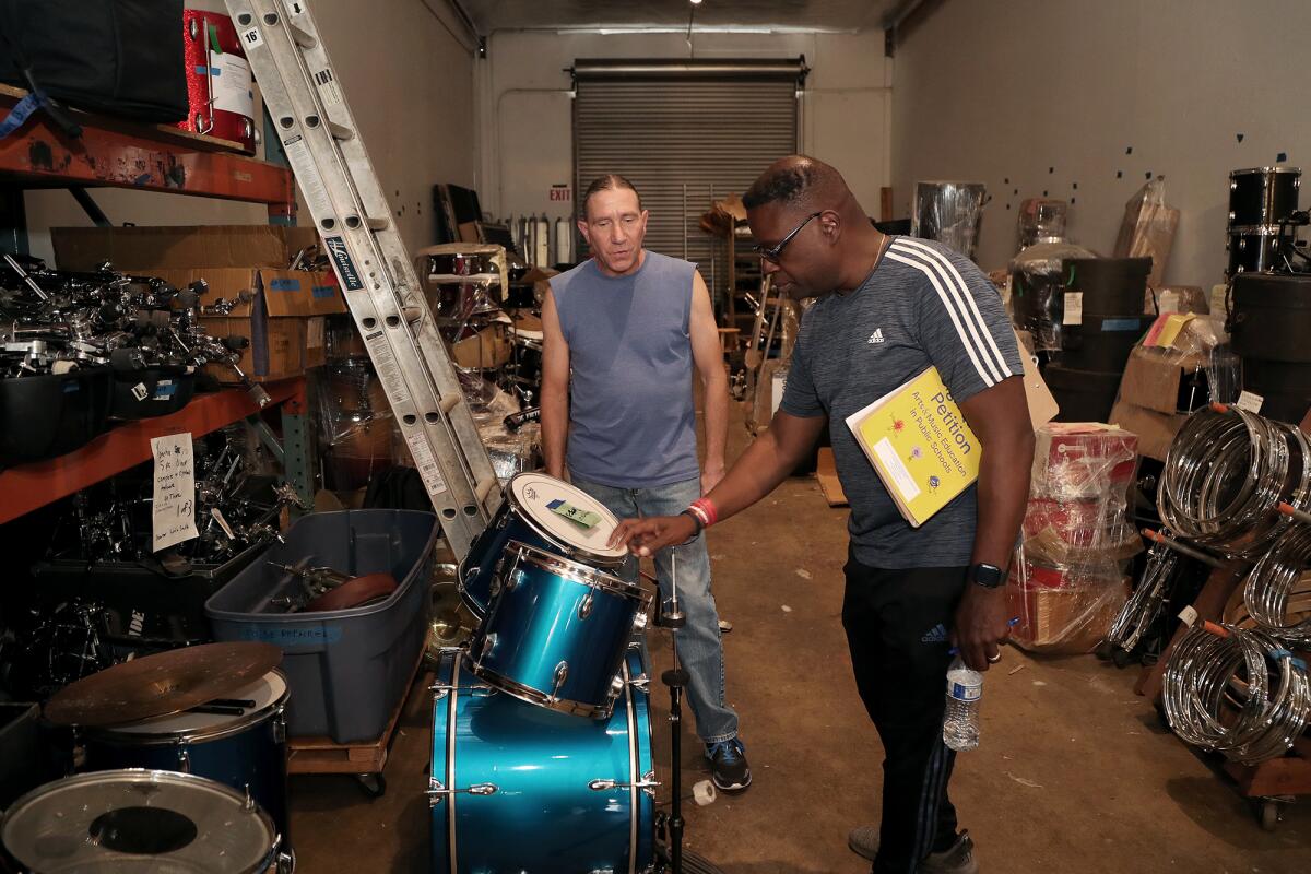 Mark Lehner, left, gives Tony White, L.A. Unified music coordinator, a drum set at Drums for Drummers in Santa Ana.