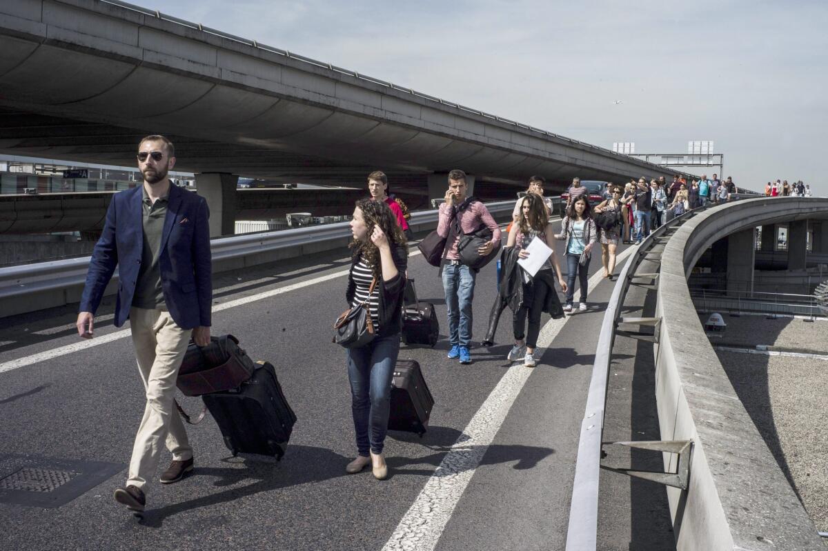 Travelers who were caught in the gridlock caused by anti-Uber protests walk along a freeway toward the Charles de Gaulle airport near Paris on June 25.