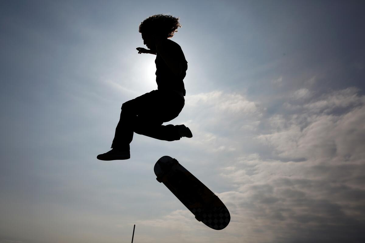 An airborne skater and his board are silhouetted against the sky.