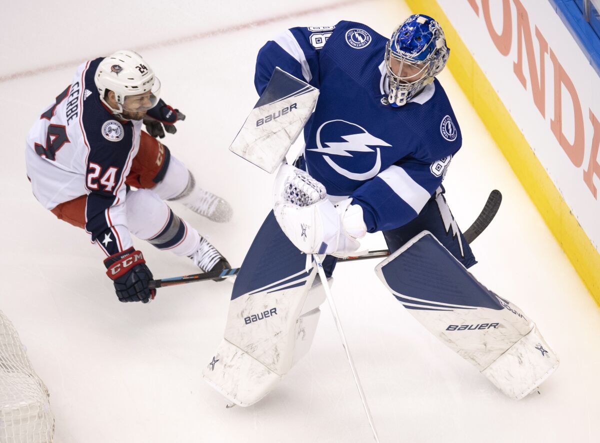 Tampa Bay Lightning goaltender Andrei Vasilevskiy (88) clears the puck under pressure from Columbus Blue Jackets center Nathan Gerbe (24) during the first period in Game 1 of an NHL hockey Stanley Cup first-round playoff series, Tuesday, Aug. 11, 2020, in Toronto. (Frank Gunn/The Canadian Press via AP)